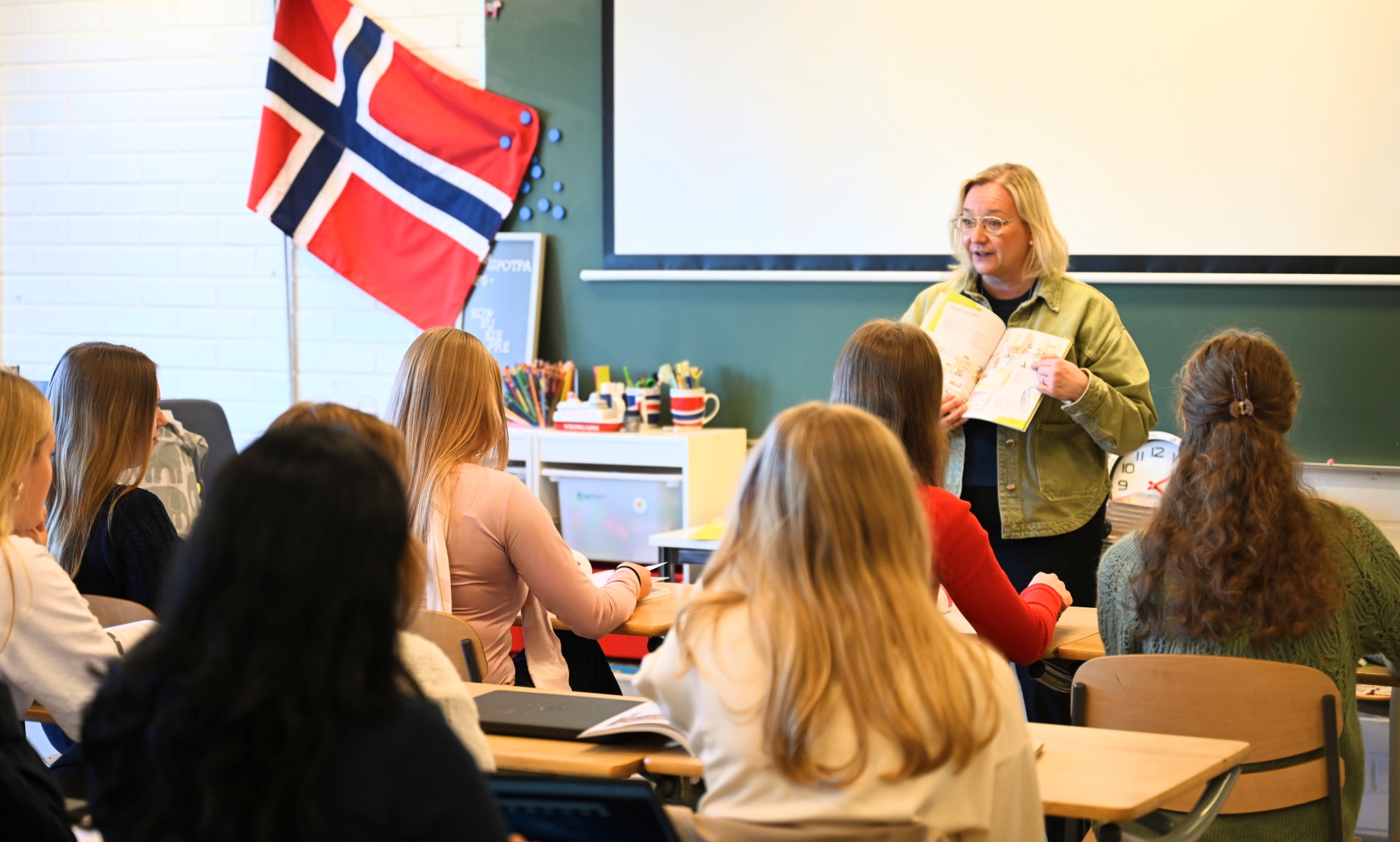 Luokkahuone, jossa oppitunti. Taustalla Norjan lippu.
